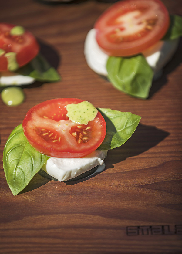 Tomat, mozzarella, basilikum och sqaush frukt på skärbrädan